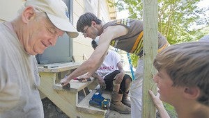 Service Over Self volunteer Ryan VanDenAkker, center, helps build new steps for a home on East Main Street Wednesday.