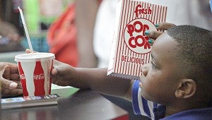 Derrick Devote Jr., 5, reaches for a refreshment Wednesday morning before going to watch Free Birds during the Wilcox Cinema Summers Kids Film Festival at the Vicksburg Mall.
