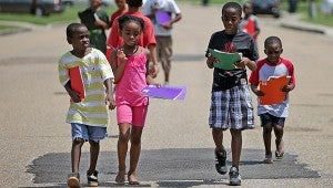 Iaisah Scott, 6, from left, Janasia Hill, 8, Tony Peterson, 9, and Rashad Scott, 5, walk home Wednesday morning after receiving school supplies from the Vicksburg Housing Authority. (Justin Sellers/The Vicksburg Post)