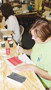 Cindy Simmons applies paint to a sample piece of wood.