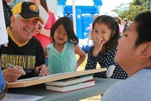 Caricature artist Ricky Nobles, left, draws a picture of Sophia Huang, 8, from left, Jenny Fang, 6, and Raymond Huang, 10, Saturday morning at the Fall Festival downtown. (Justin Sellers/The Vicksburg Post)