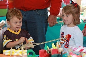 Lucas Robert, 4, left, and Madison Connelly, 4, play with a wooden fishing pole Saturday morning on Jackson Street during the Old Court House Flea Market. (Justin Sellers/The Vicksburg Post)