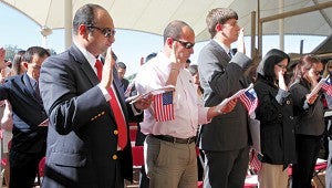 Dr. Sunit Sebastian, left, holds an American flag as he recites the oath of allegiance during a naturalization ceremony at the USS Cairo at Vicksburg National Military Park. 