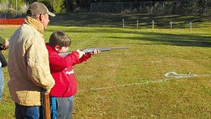 YOUNG SHOOTER: Redwood third-grader Dalton Roy takes aim at a circle target as his grandfather, Dwayne Roy, looks on. Dalton, 8, was one of several younger shooters who took part in the school PTO’s annual turkey shoot on the school grounds. Dalton’s father, Josh Roy, who didn’t shoot, stood behind his son as an observer. It was Dalton’s third year to shoot at the event.