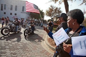 Patricia Daniel waves an American flag as motorcycles file past Tuesday morning during the annual Veterans Day parade on Washington Street in downtown Vicksburg. (Justin Sellers/The Vicksburg Post)
