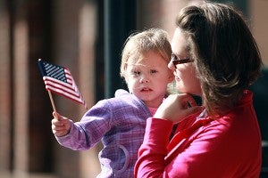 Morgan Poe, 3, held by Brandy Poe, waves an American flag Tuesday morning during the annual Veterans Day parade on Washington Street in downtown Vicksburg. (Justin Sellers/The Vicksburg Post)