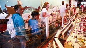 HOLIDAY CITY: Shughnessy Baker, left, Tyshonna Curtis and Morgan Baker look at a model train inside the Kansas City Southern Holiday Express during its visit to Vicksburg on Friday. Inside the train was decorated with model railroads and winter scenes.