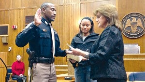 Central District Constable Troy Kimble, left, places his hand on a Bible held by his wife, Latoria Kimble, as he is sworn in by Chancery Clerk Donna Hardy.
