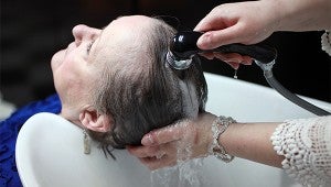 Hairstylist McMillan Crevitt washes the hair of Joan Leese at Southern Barber and Style Shop. (Justin Sellers/The Vicksburg Post)