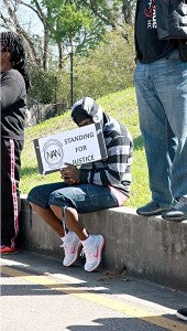 WAITING FOR JUSTICE: A protester looks up from behind a sign at the protest demonstration and march held in Port Gibson Saturday. 