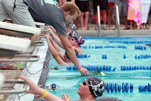 Vicksburg Swim Association coach Mathew Mixon drops a white rose into an empty lane honoring Afton Wallace Sunday before the Girls 100 meter backstroke during the Stamm Family Invitational at City Pool. 