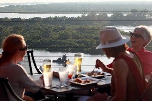 A tug passes by in the Yazoo River Diversion Canal as diners enjoy their dinner at 10 South Rooftop Bar and Grill Monday evening during the second night of their soft opening. The rooftop restaurant is opening to the public Wednesday.