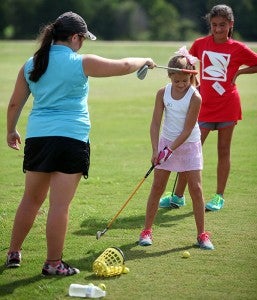 Warren Central golfer Karley Whittington helps Luci Madison, 8, keep her head down through her swing Tuesday morning during the Clear Creek golf camp. (Justin Sellers/The Vicksburg Post)